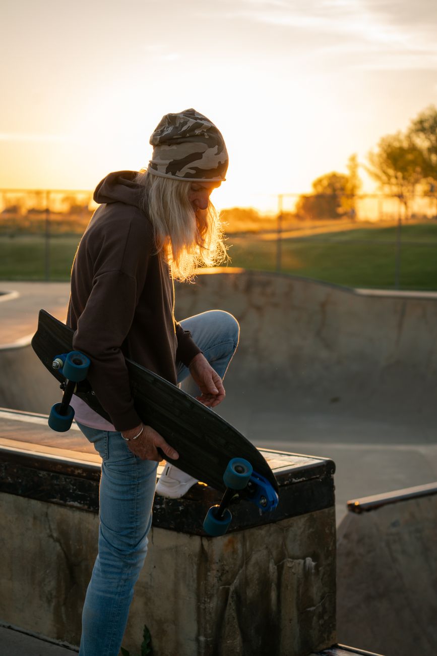 Skateboarder holding his board at sunset