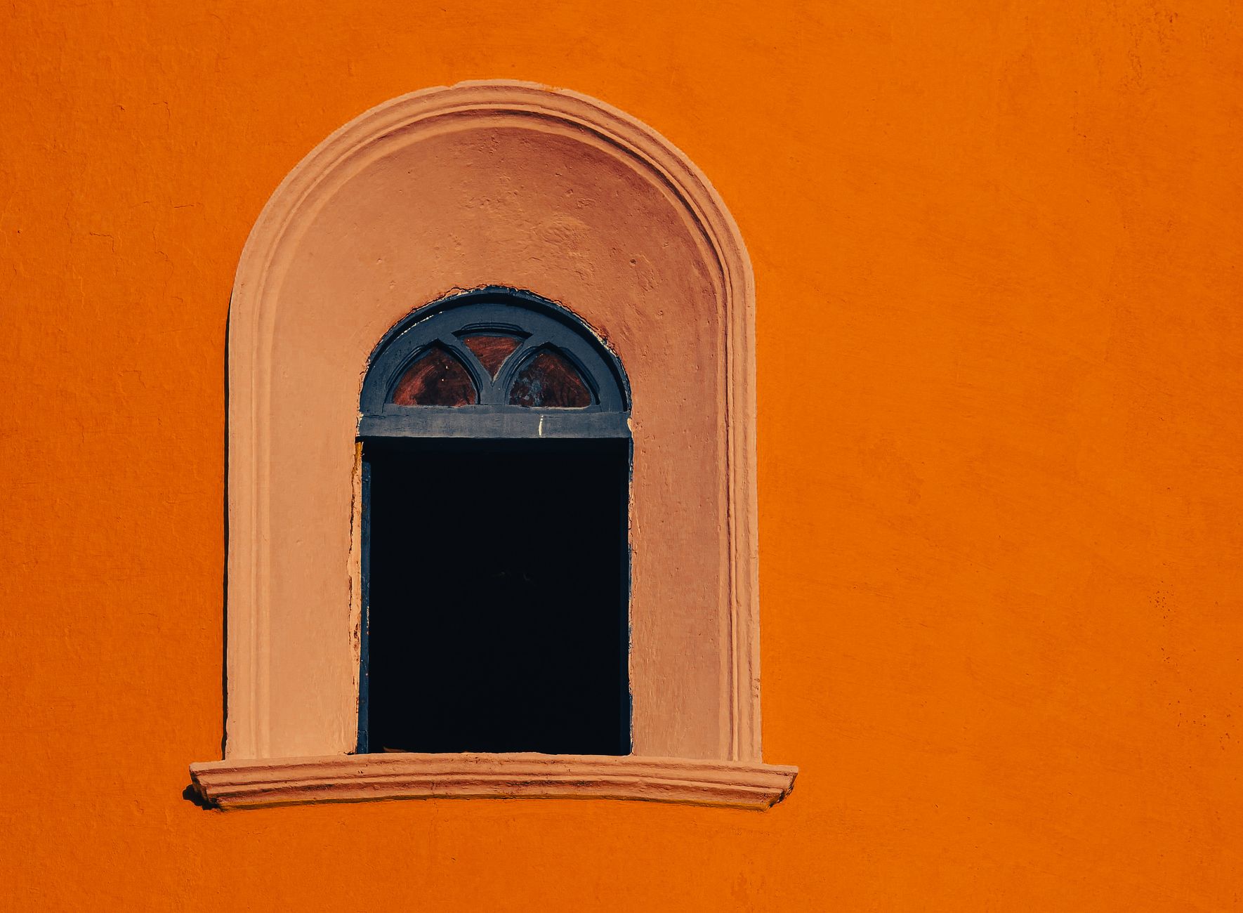 Arched doorway in a terracotta wall painted bright orange