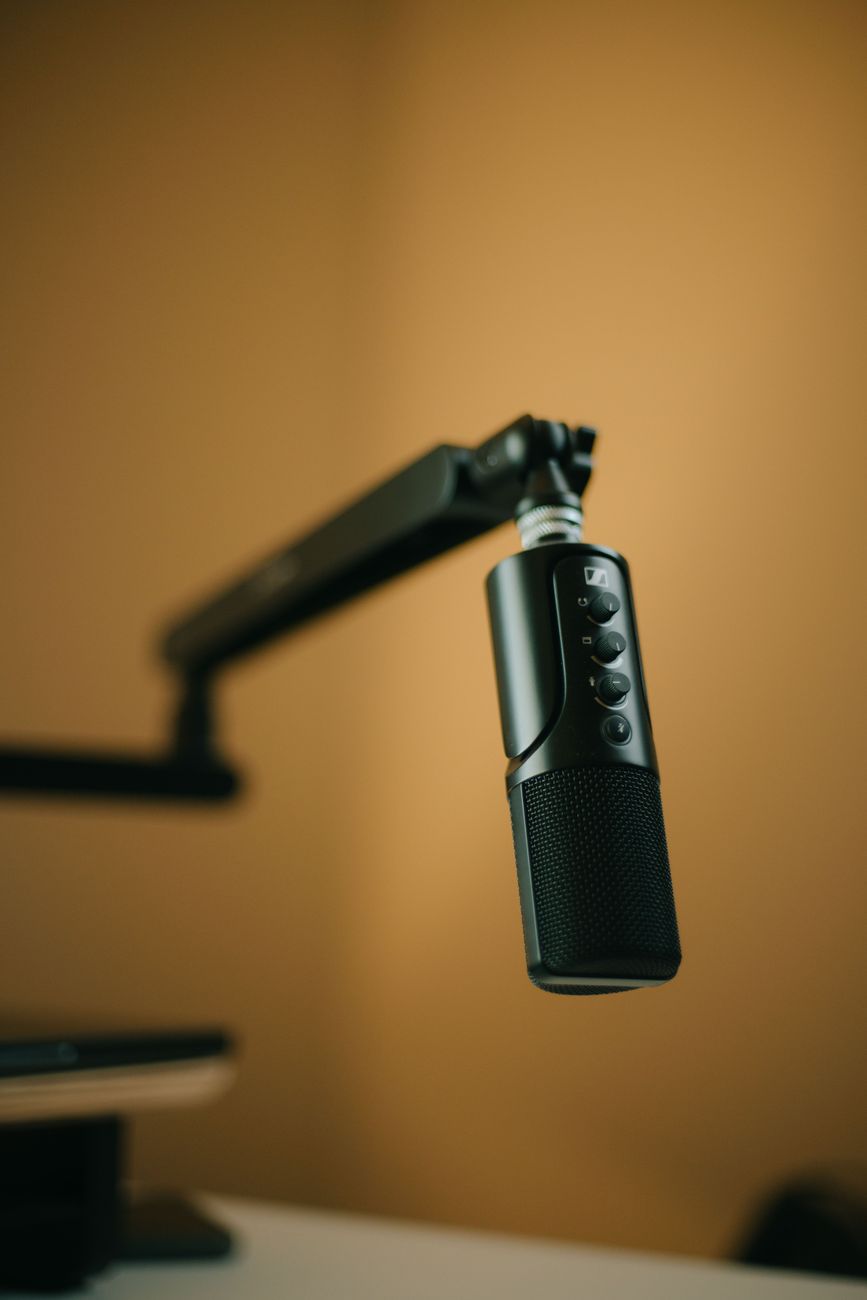 Studio microphone on an arm against a warm ochre wall