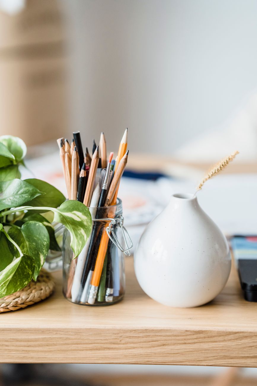 Jar of pencils and a white vase on a studio desk
