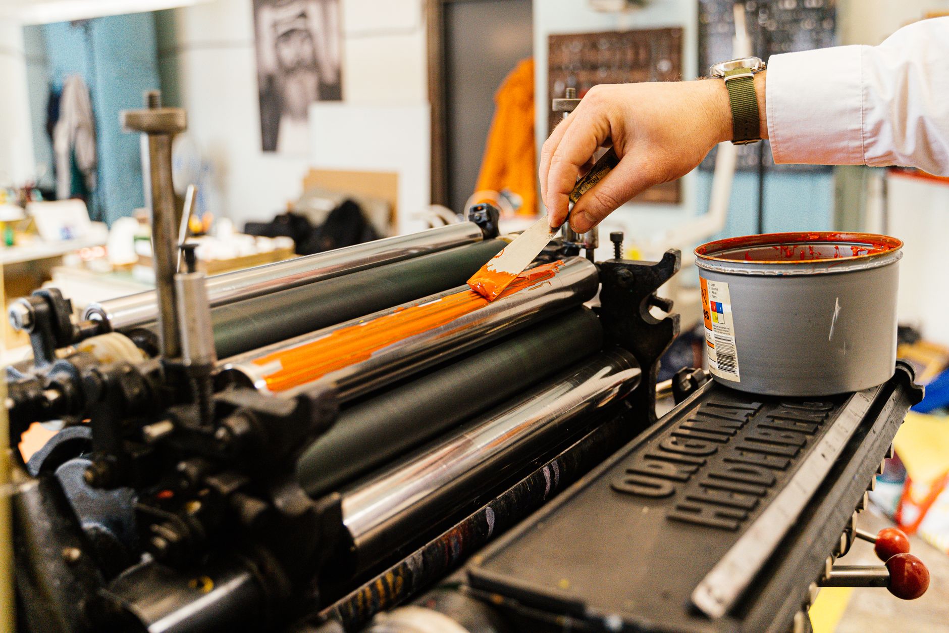 A hand inking the rollers of a letterpress machine