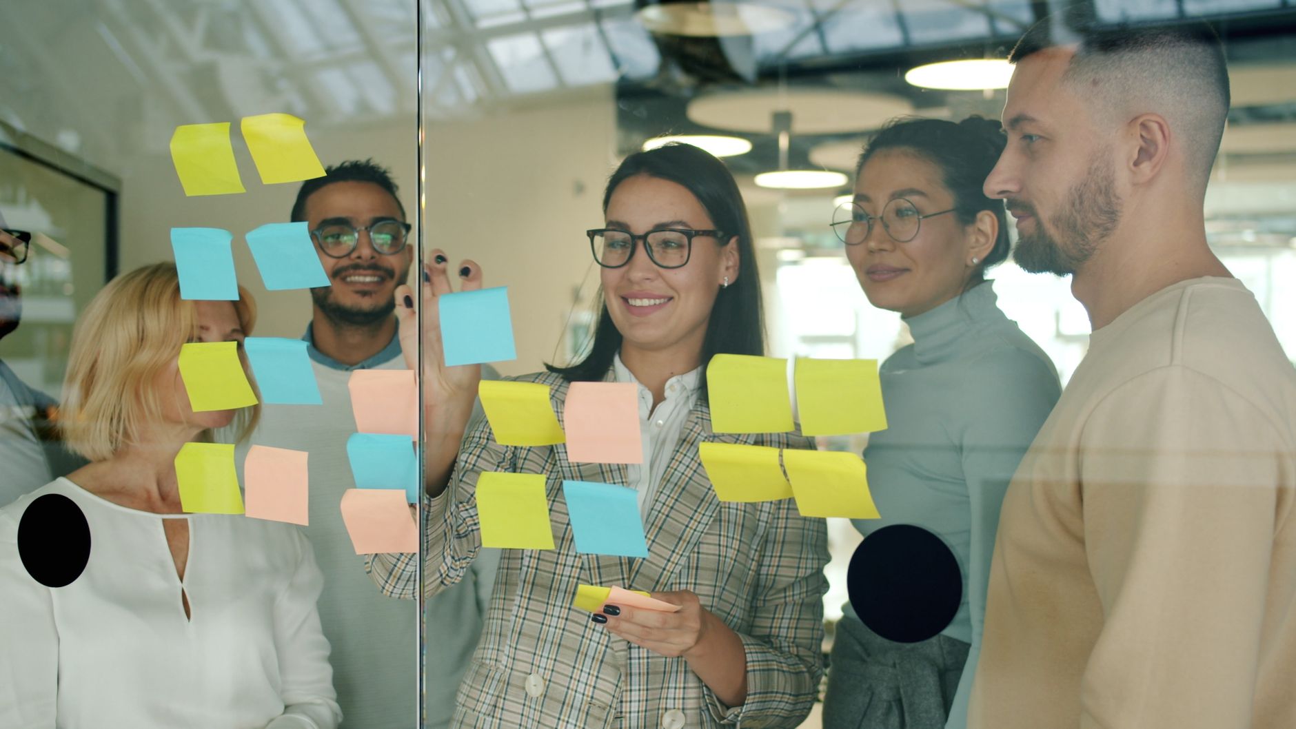 Team arranging sticky notes on a glass wall