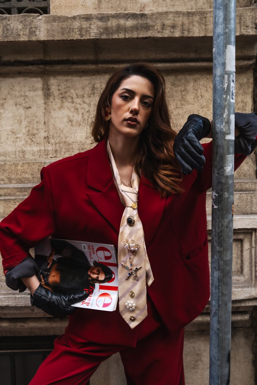 Portrait of a woman in a red suit leaning on a street pole