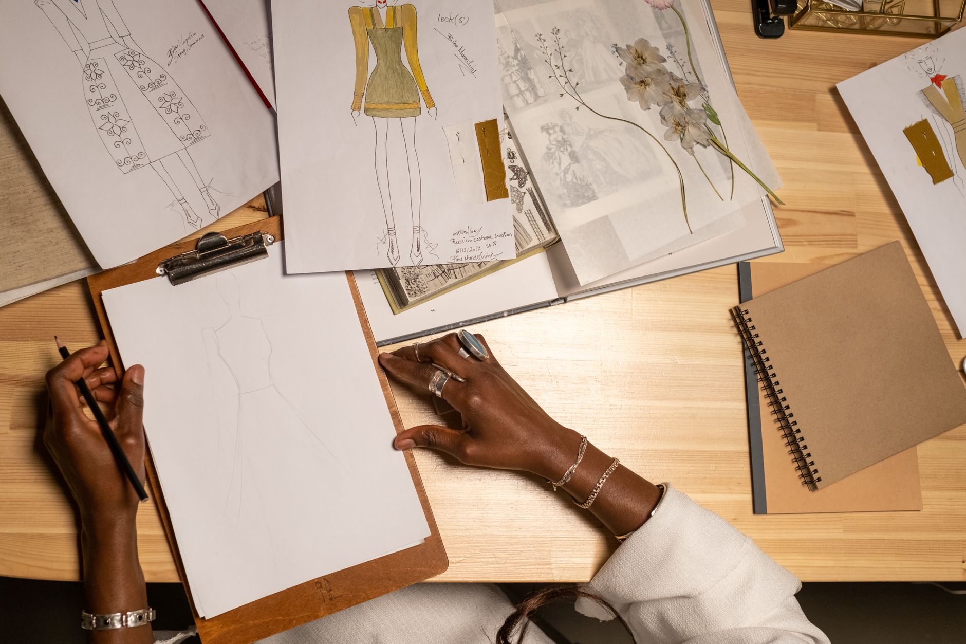 Designer sketching fashion drawings on a clipboard