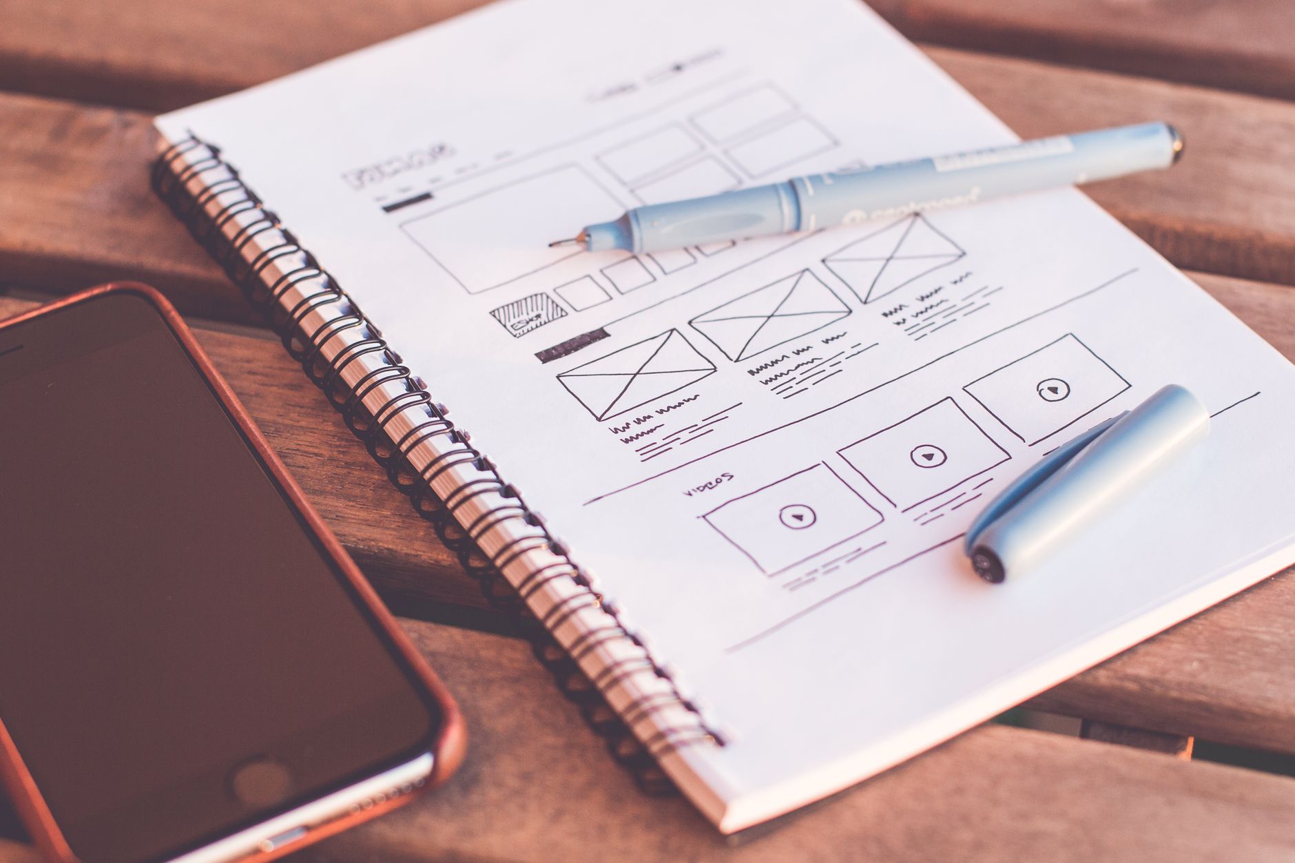 Wireframe sketches in a notebook beside a phone