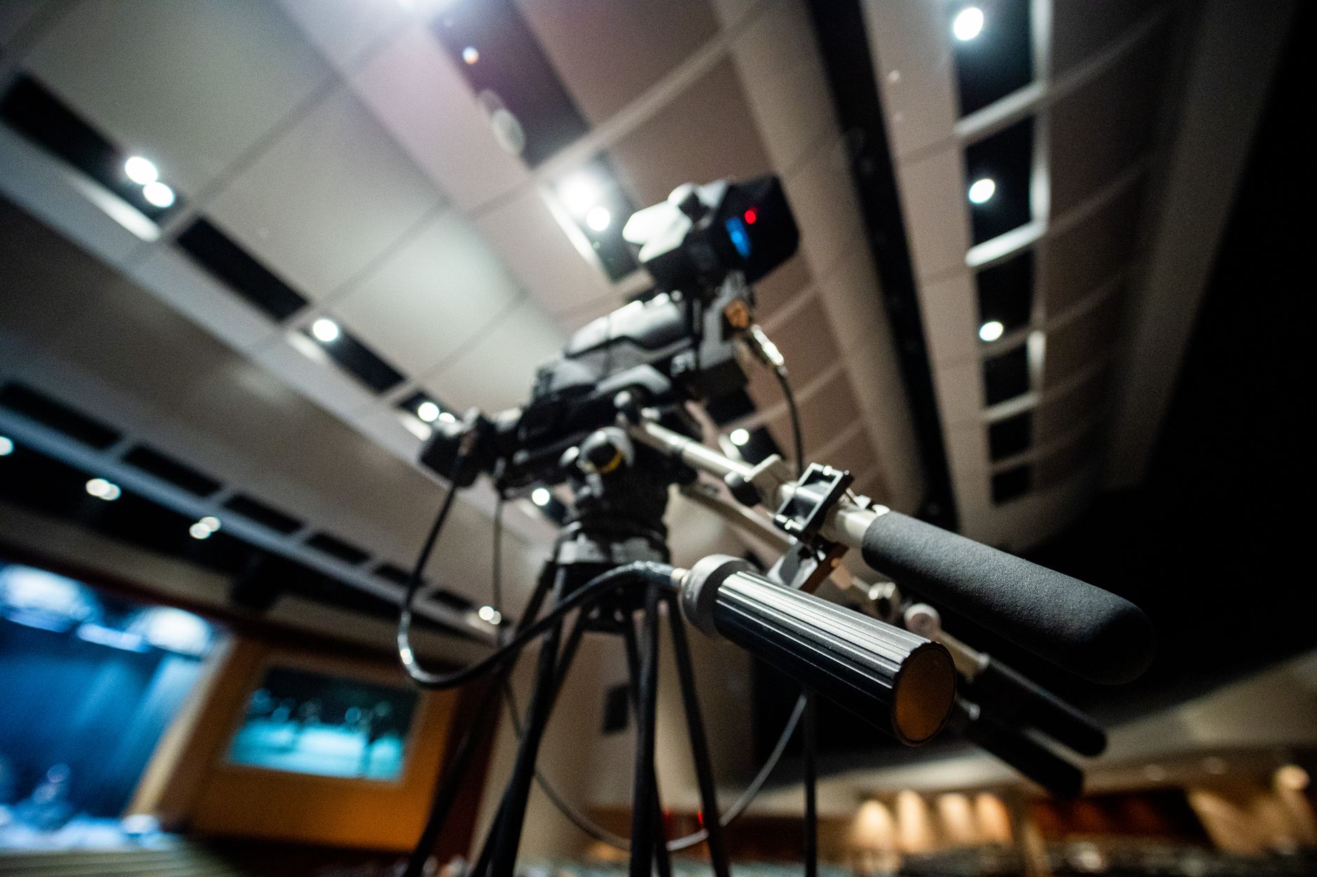 Film camera on a tripod in a lit auditorium