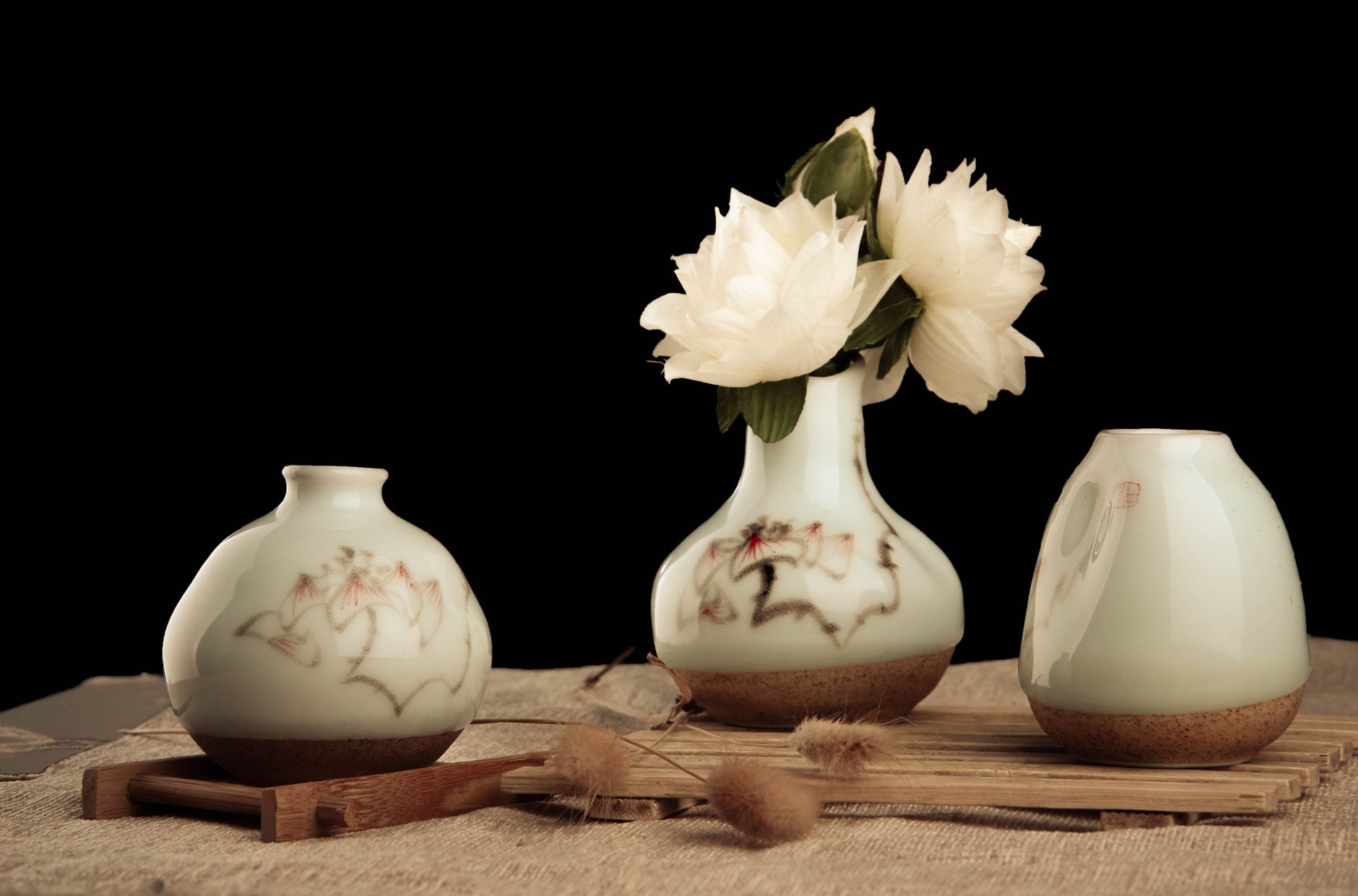 Three ceramic vases with white flowers on a dark ground